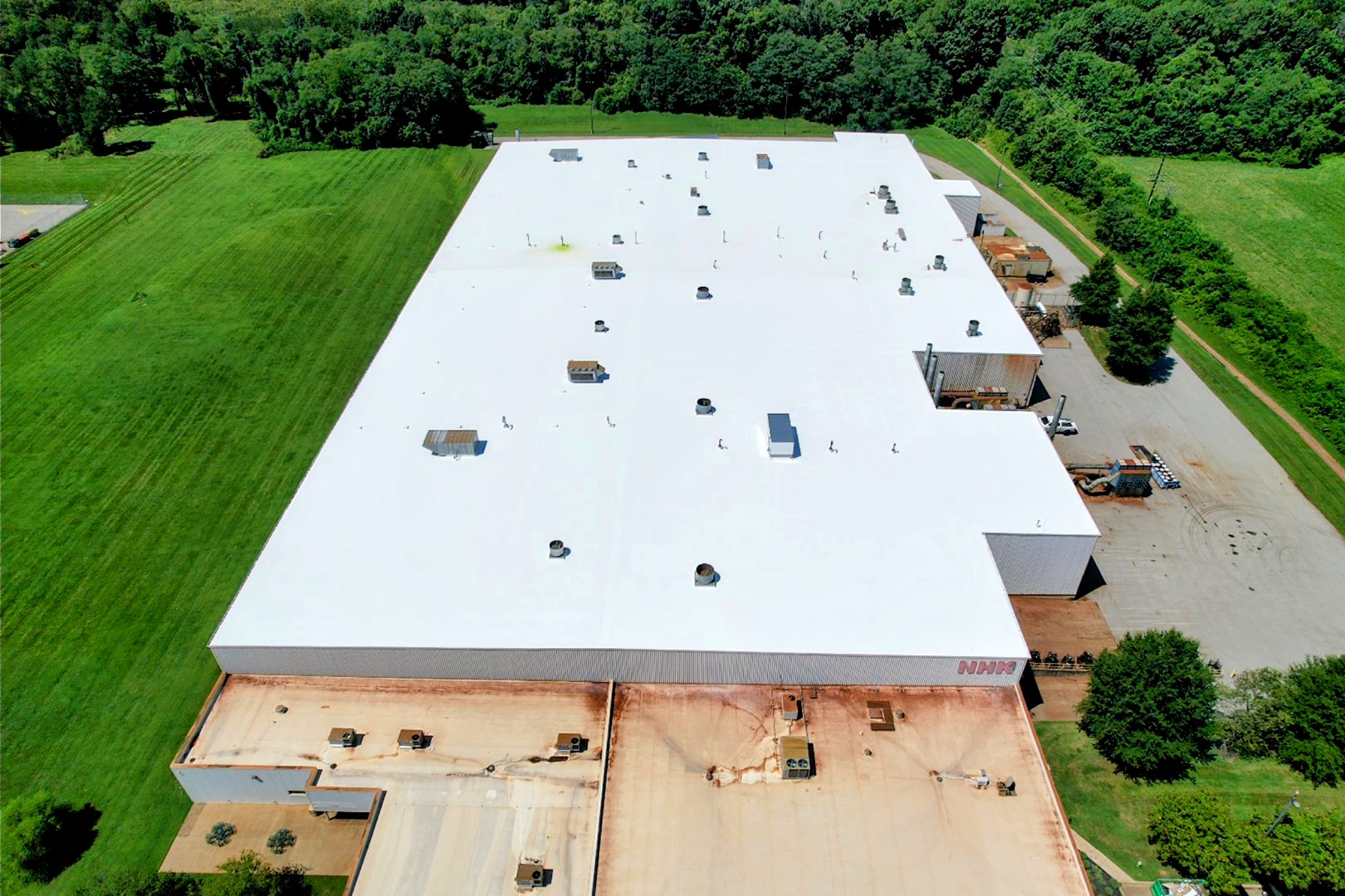 Aerial view of a commercial warehouse roof restored with a bright white silicone roof coating near Bowling Green, KY